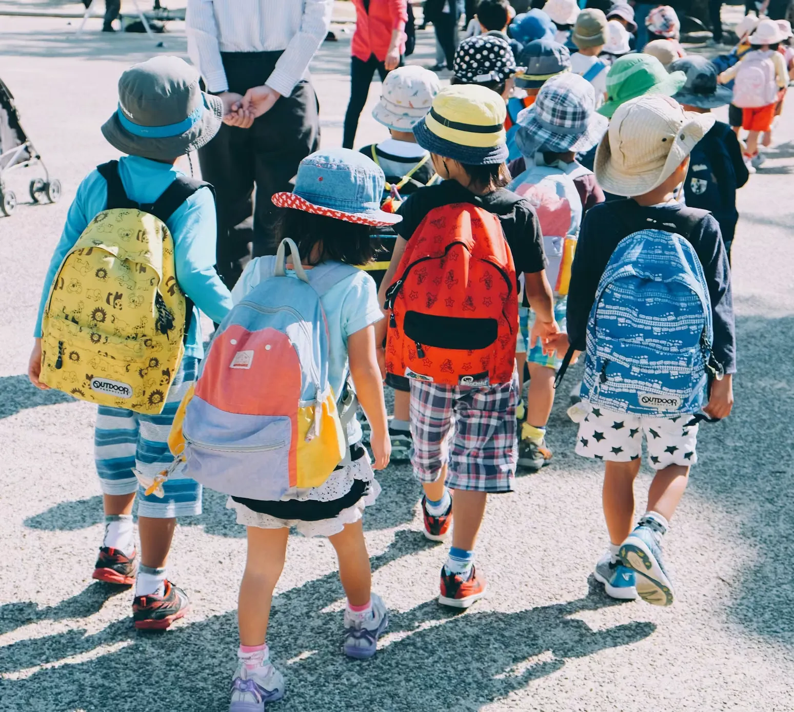 Schulkinder von hinten mit Rucksäcken